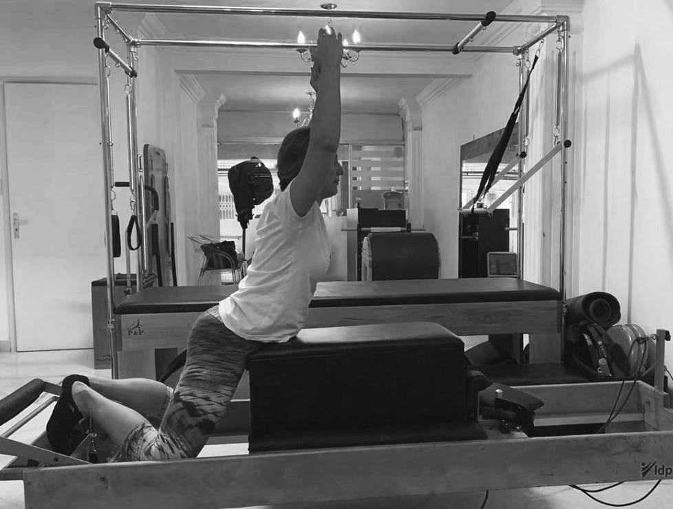 mujer realizando ejercicio de pilates reformer conocido como swan