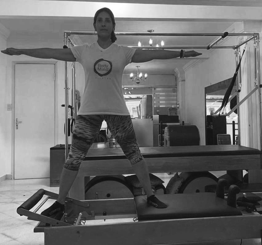 mujer realizando ejercicio de pilates reformer conocido como side splits