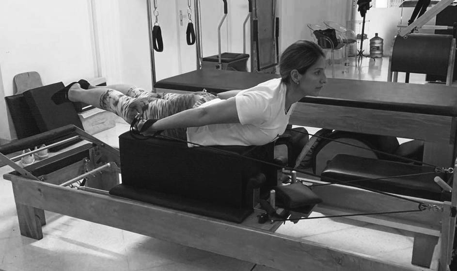 mujer realizando ejercicio de pilates reformer conocido como pulling straps