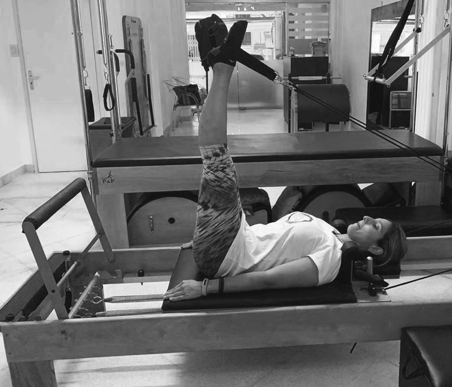 mujer realizando ejercicio de pilates reformer conocido como lower and lift